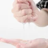 Hands holding and squeezing clear gel or serum dripping VEZE Gold Hyaluronic Acid Facial Mask moisturizing skincare sheet mask for glowing and hydrated skin
